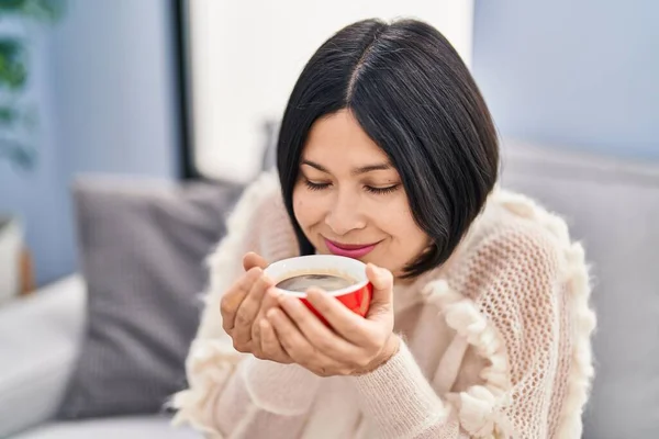 Young Chinese Woman Smelling Coffee Sitting Sofa Home — Stockfoto