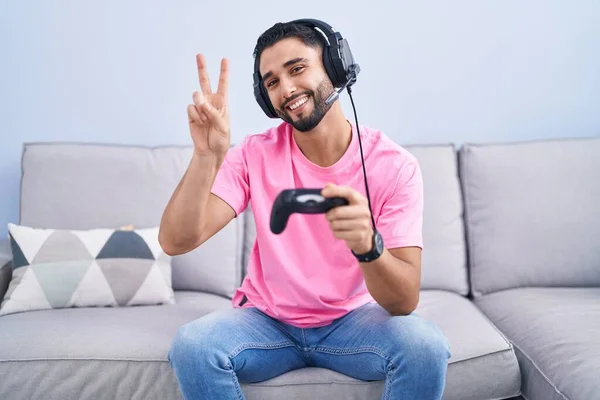 Hispánský Mladý Muž Který Hraje Videohru Ovladačem Sedícím Pohovce Usmívá — Stock fotografie
