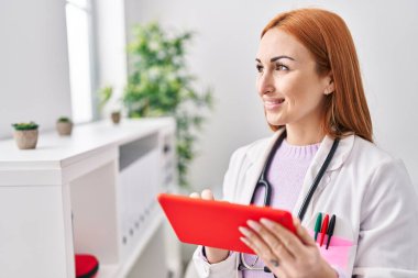 Genç beyaz kadın doktor klinikte dokunmatik ped kullanıyor.