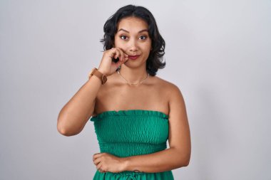 Young hispanic woman standing over isolated background mouth and lips shut as zip with fingers. secret and silent, taboo talking 