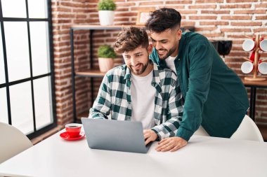Young couple using laptop sitting on table at home