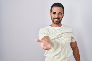 Arka planda sakallı, neşeli gülümseyen, yardım eli uzatan ve kabul gören İspanyol bir adam.. 