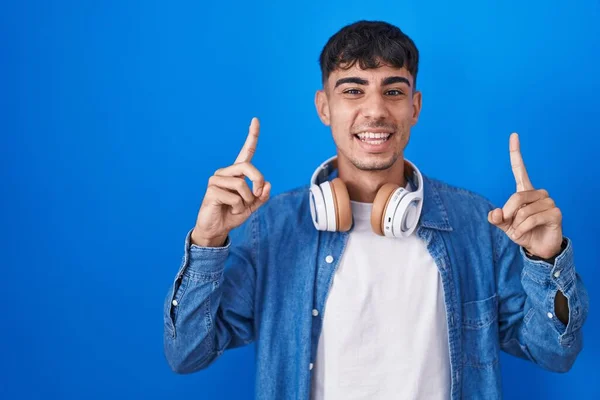 Jovem Hispânico Homem Sobre Fundo Azul Sorrindo Espantado Surpreso Apontando — Fotografia de Stock