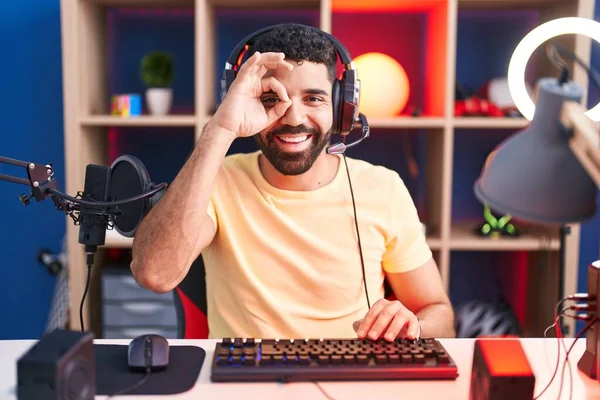 髭を生やしているヒスパニック系の男ビデオゲームとともにヘッドフォンDoing Okジェスチャーとともに手笑顔 目を通して見て指で幸せな顔 — ストック写真