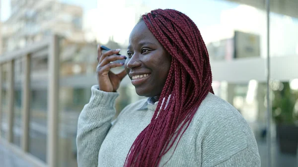 戴辫子的非洲女人在街上用智能手机听着语音信息 — 图库照片