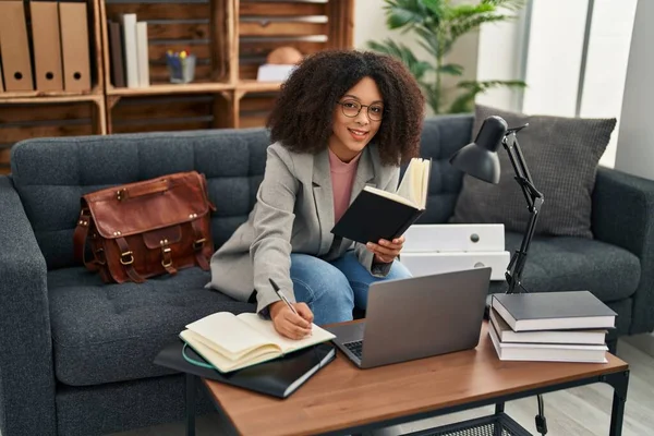 年轻的非洲裔美国女心理学家在心理中心使用笔记本电脑和书写书籍 — 图库照片