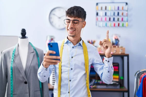 Young Hispanic Man Dressmaker Designer Using Smartphone Smiling Happy Pointing — Stock Photo, Image
