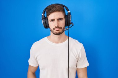 Sakallı, kulaklık takmış, kederli, sinirli ve korkmuş bir şekilde müzik dinleyen İspanyol bir adam. hüzünlü ifade. 