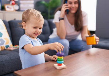 Anne ve oğlu akıllı telefondan konuşuyor. Evde kahve içip oynuyorlar.