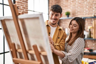 Resim stüdyosunda gülümseyen kadın ve erkek sanatçı.