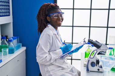 African american woman scientist writing report working at laboratory
