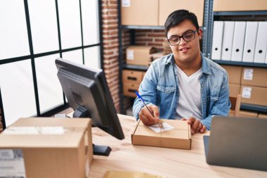 Down sendromlu adam ecommerce işadamı ofiste paket üzerine yazıyor.