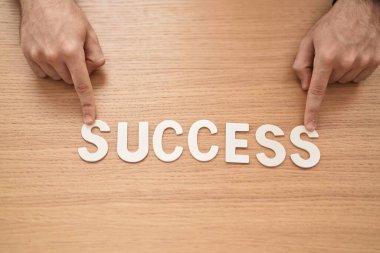 Kafkasyalı genç bir iş adamı ofiste başarı sözcüğüyle masada oturuyor.