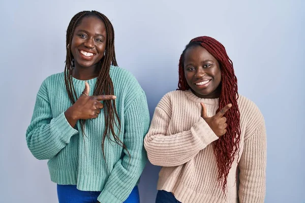 Две Африканки Стоящие Синем Фоне Веселые Улыбкой Лице Указывающей Рукой — стоковое фото
