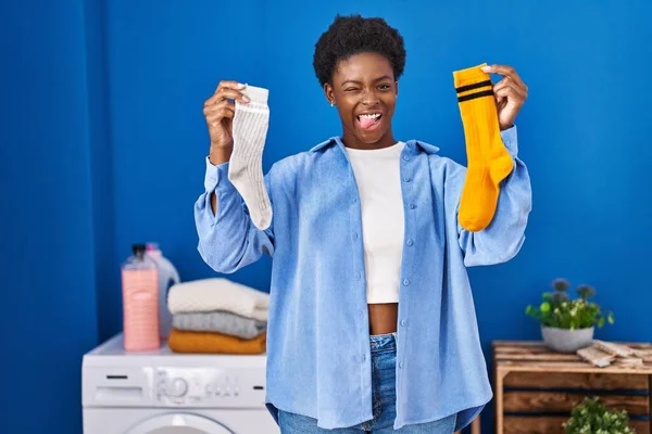 拿着干净而又脏的袜子的非洲裔美国女人带着滑稽的表情高兴地伸出舌头 — 图库照片