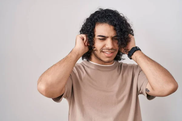 西班牙男人 卷曲的头发 站在白色的背景上 用手指捂住耳朵 对嘈杂的音乐感到恼怒 聋人概念 — 图库照片