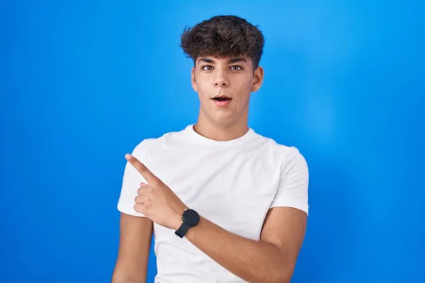 Ισπανόφωνος Έφηβος Στέκεται Πάνω Από Μπλε Φόντο Έκπληκτος Δείχνοντας Δάχτυλο — Φωτογραφία Αρχείου