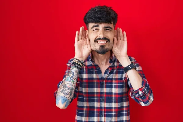 Young Hispanic Man Beard Standing Red Background Trying Hear Both — Stock Photo, Image