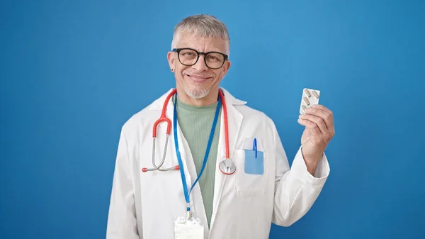 Середнього Віку Сірошерстий Чоловік Лікар Тримає Таблетки Над Ізольованим Синім — стокове фото