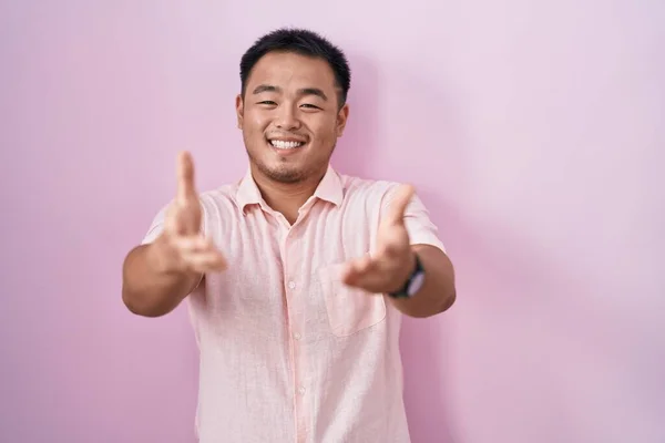 Китайський Молодий Чоловік Стоїть Над Рожевим Фоном Усміхається Радістю Пропонуючи — стокове фото