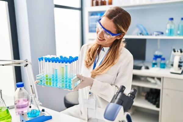 身穿科学家制服的金发女青年拿着试管在实验室里 — 图库照片