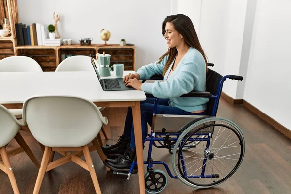 stock image Young woman using laptop sitting on wheelchair working at home