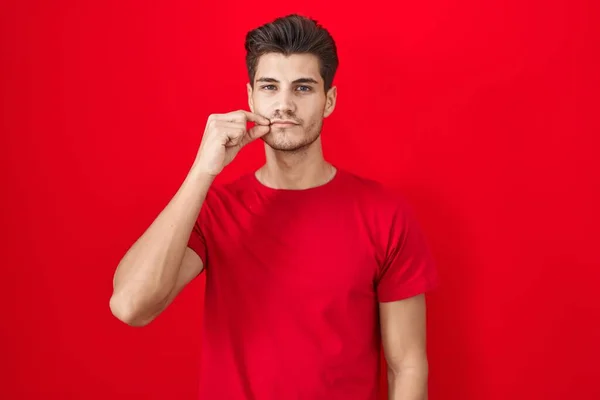 Homem Hispânico Jovem Sobre Boca Fundo Vermelho Lábios Fechados Como — Fotografia de Stock