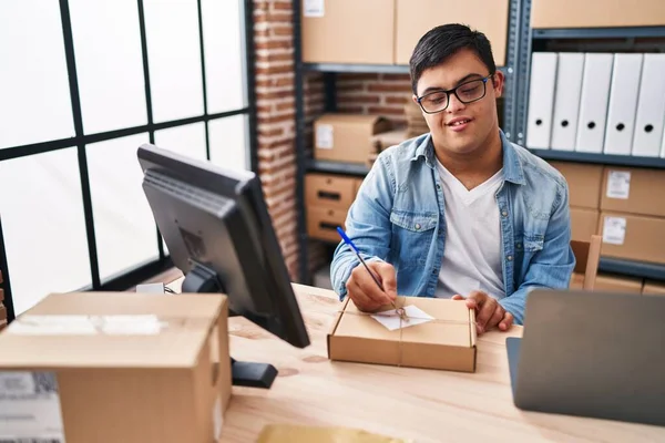 stock image Down syndrome man ecommerce business worker writing on package at office