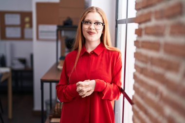 Young redhead woman business worker smiling confident standing at office