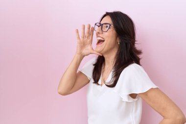 Orta yaşlı İspanyol kadın, günlük beyaz tişört ve gözlük giyip el ele tutuşarak bağırıyor ve bağırıyordu. iletişim konsepti. 