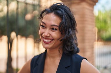Young beautiful hispanic woman smiling confident looking to the side at street