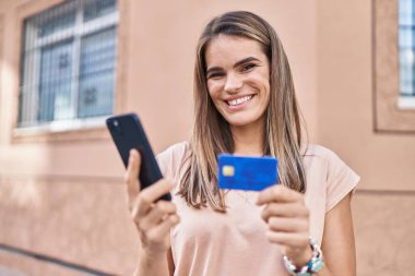 Genç ve güzel İspanyol kadın akıllı telefon ve kredi kartı kullanıyor.