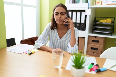 Genç Afro-Amerikan kadın iş kadını. Ofiste çalışan akıllı telefondan konuşuyor.