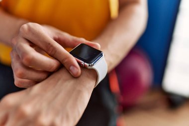 Genç sarışın adam spor merkezinde kronometreye dokunuyor.