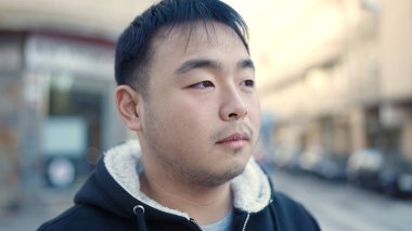 Young chinese man looking to the side with serious expression at street