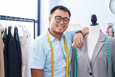 Genç Çinli terzi terzide kendine güvenen manikürcüye gülümsüyor.