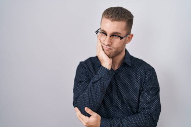 Tecrit edilmiş arka planda duran genç beyaz adam çapraz kollarla depresyon sorunlarından sıkılmış ve yorgun göründüğünü düşünüyor.. 