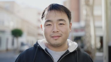 Young chinese man smiling confident standing at street