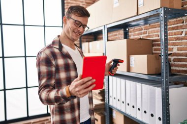 Young man ecommerce business worker scanning package using touchpad at office