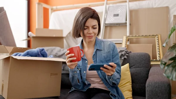 Beyaz Kadın Akıllı Telefon Kullanıyor Yeni Evinde Kahve Içiyor — Stok fotoğraf