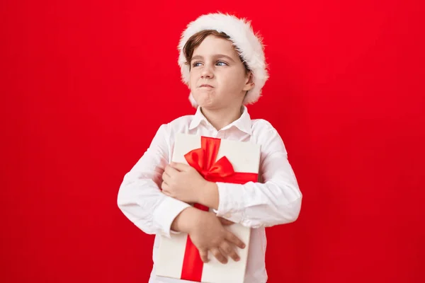 Malý Běloch Nosí Vánoční Čepici Drží Dárky Úsměvem Dívá Stranou — Stock fotografie