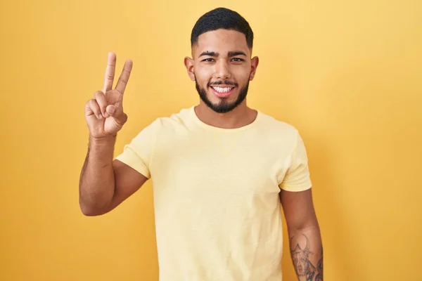 Junger Hispanischer Mann Der Vor Gelbem Hintergrund Steht Und Lächelnd — Stockfoto