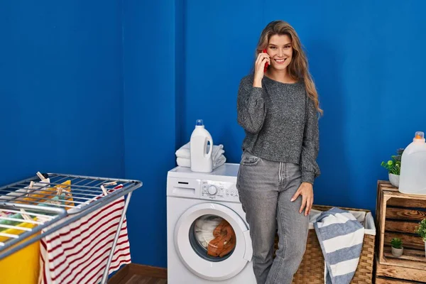 Akıllı Telefonda Konuşan Genç Sarışın Kadın Çamaşır Odasında Çamaşır Makinesini — Stok fotoğraf