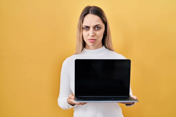Mulher Loira Jovem Segurando Laptop Cético Nervoso Franzindo Testa Chateado — Fotografia de Stock