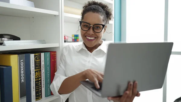 アフリカ系アメリカ人の学生は図書館大学でノートパソコンを使って自信を持って笑っています — ストック写真