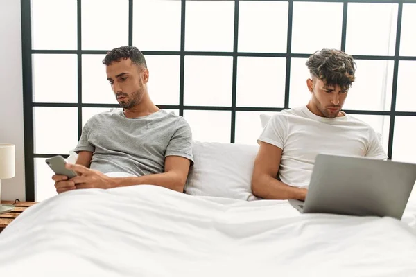 Två Latinamerikanska Män Par Använder Laptop Och Smartphone Sitter Sängen — Stockfoto