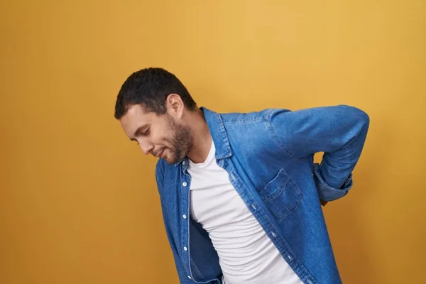 Hispanic Man Standing Yellow Background Suffering Backache Touching Back Hand — Stockfoto
