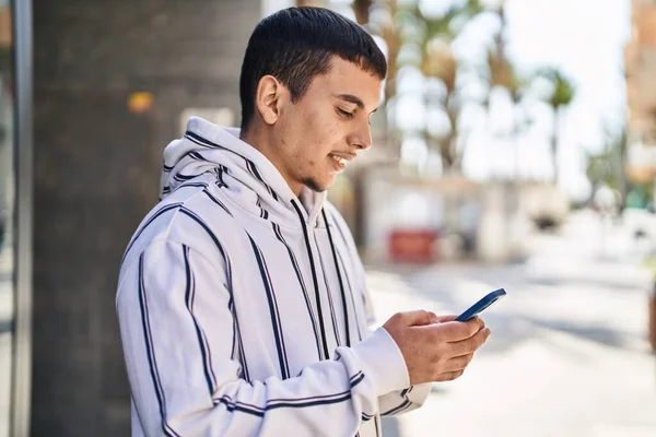 Junger Mann Lächelt Selbstbewusst Mit Smartphone Auf Der Straße — Stockfoto