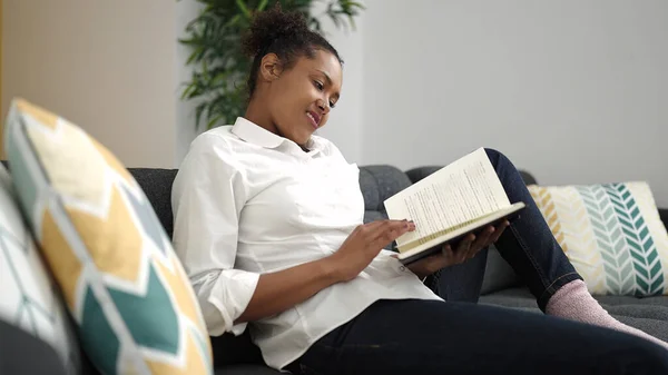 African American Woman Reading Book Sitting Sofa Home —  Fotos de Stock