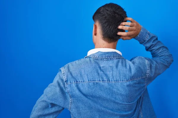 Νεαρός Ισπανόφωνος Στέκεται Πάνω Από Μπλε Φόντο Προς Πίσω Σκεπτόμενος — Φωτογραφία Αρχείου